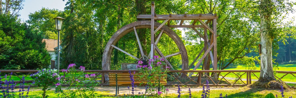 Historisches Wasserrad Historisches Wasserrad mit Blumenbeet im Vordergrund