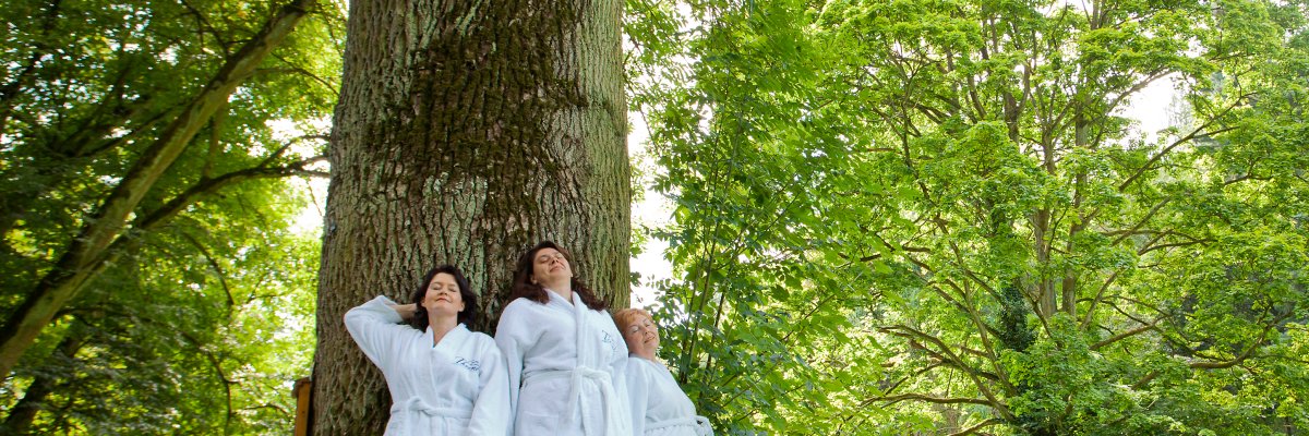 Frauen am Baum Drei Frauen am Baum im weißen Bademantel lehnen sich mit dem Rücken an einen dicken Baum.